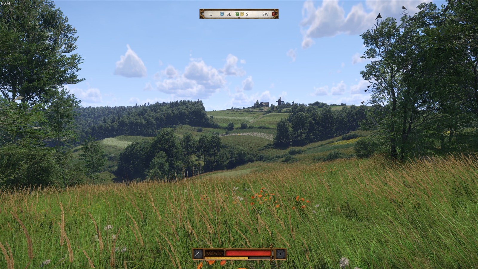 In-game view across grassy hills and trees toward a distant windmill, with the game HUD visible.